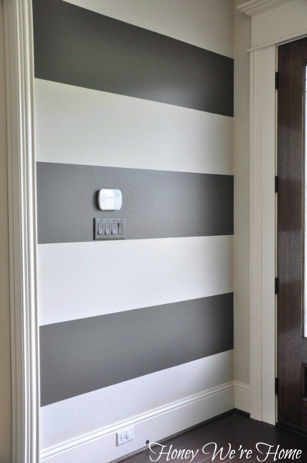 a white and gray striped wall in a room with a light switch on the side