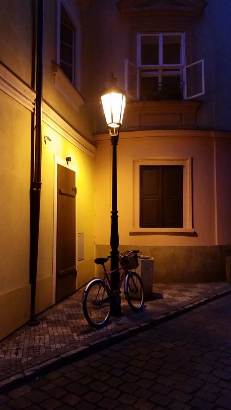 a bicycle parked on the side of a street next to a lamp post at night