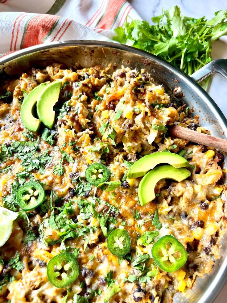 a skillet filled with mexican food and topped with avocado