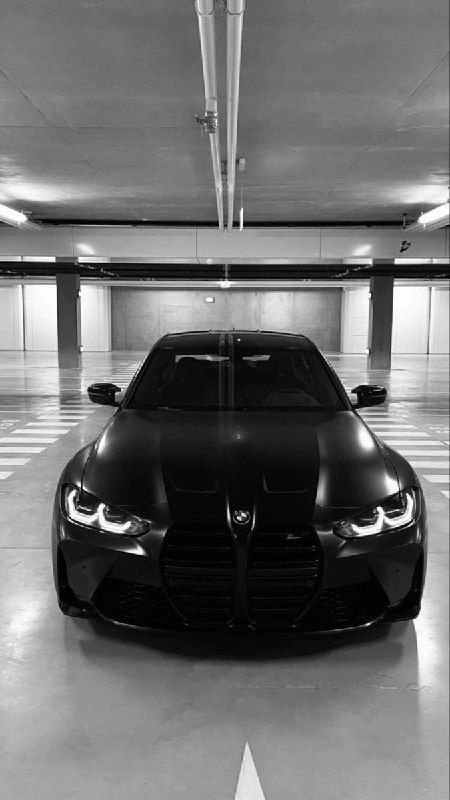 a black and white photo of a car in a parking garage with no one around