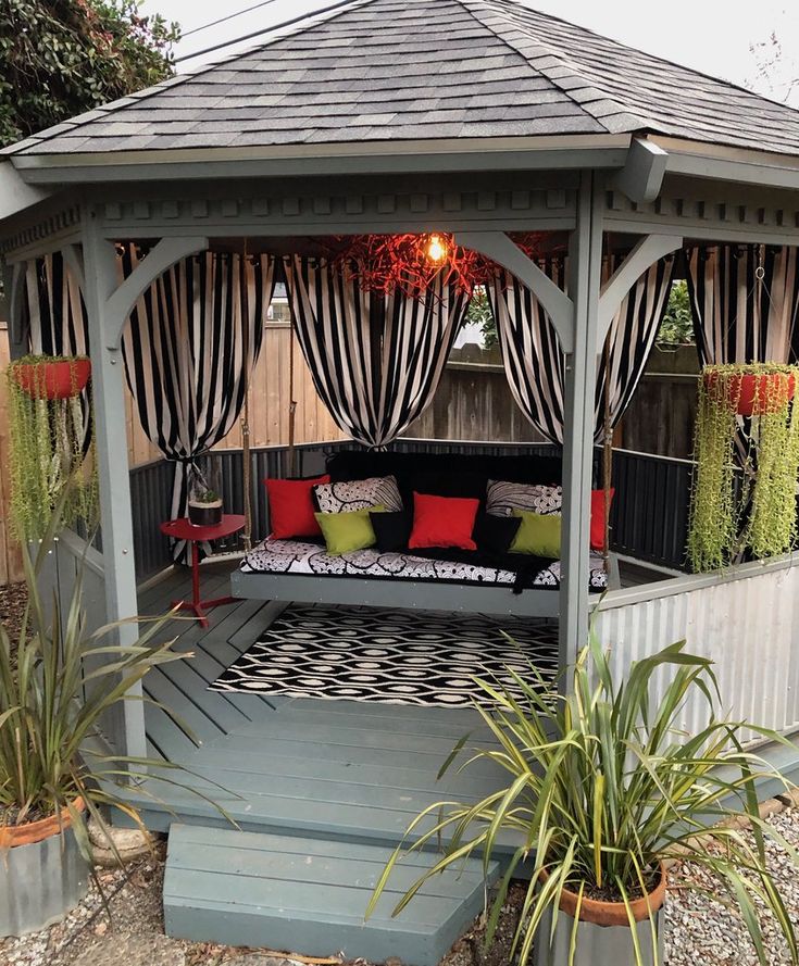 a bed sitting under a wooden gazebo surrounded by plants