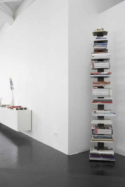 a stack of books sitting on top of a black floor next to a white wall