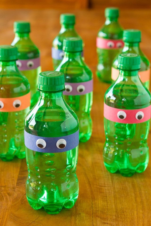 green water bottles with faces painted on them sitting on a wooden table, ready to be eaten