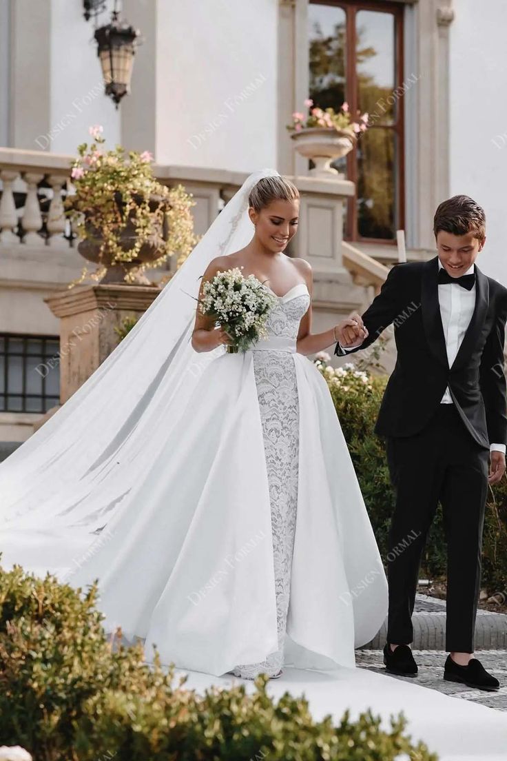 the bride and groom are walking down the steps together in their wedding attire, holding hands