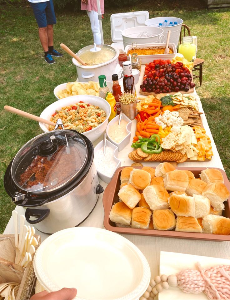 a table filled with lots of food on top of a grass covered field