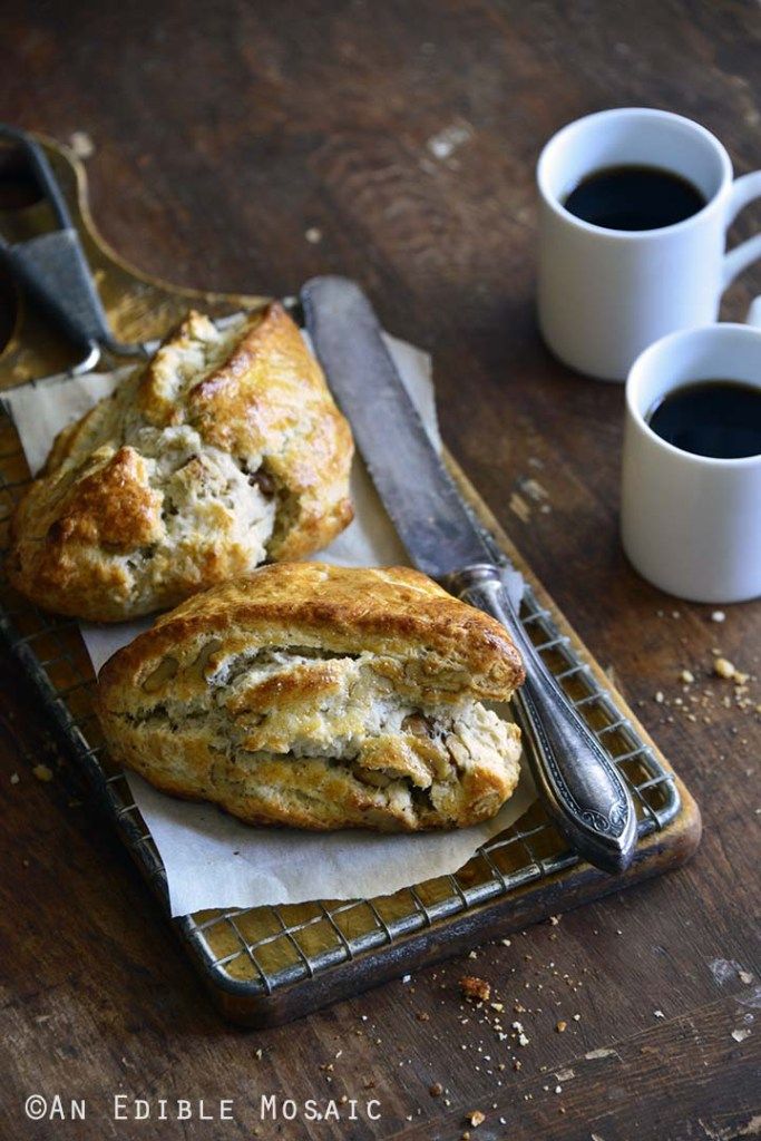 two pastries sitting on top of a metal tray next to coffee cups and spoons