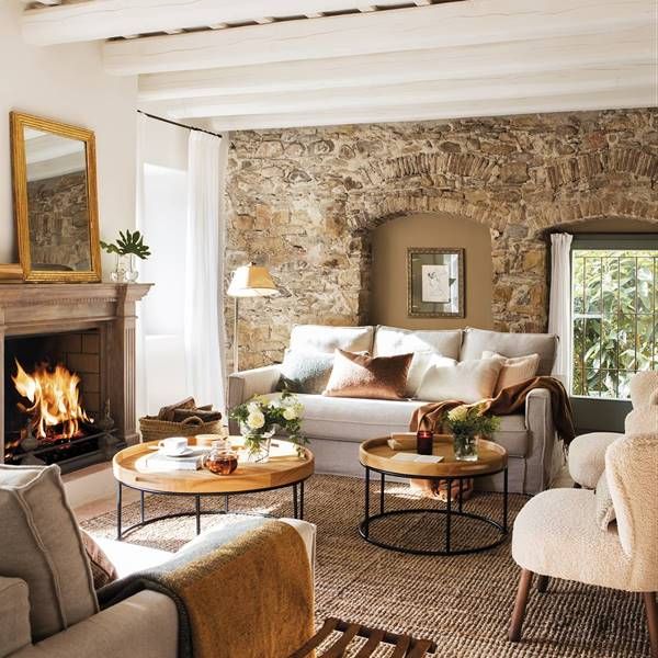 a living room filled with furniture and a fire place in front of a stone wall