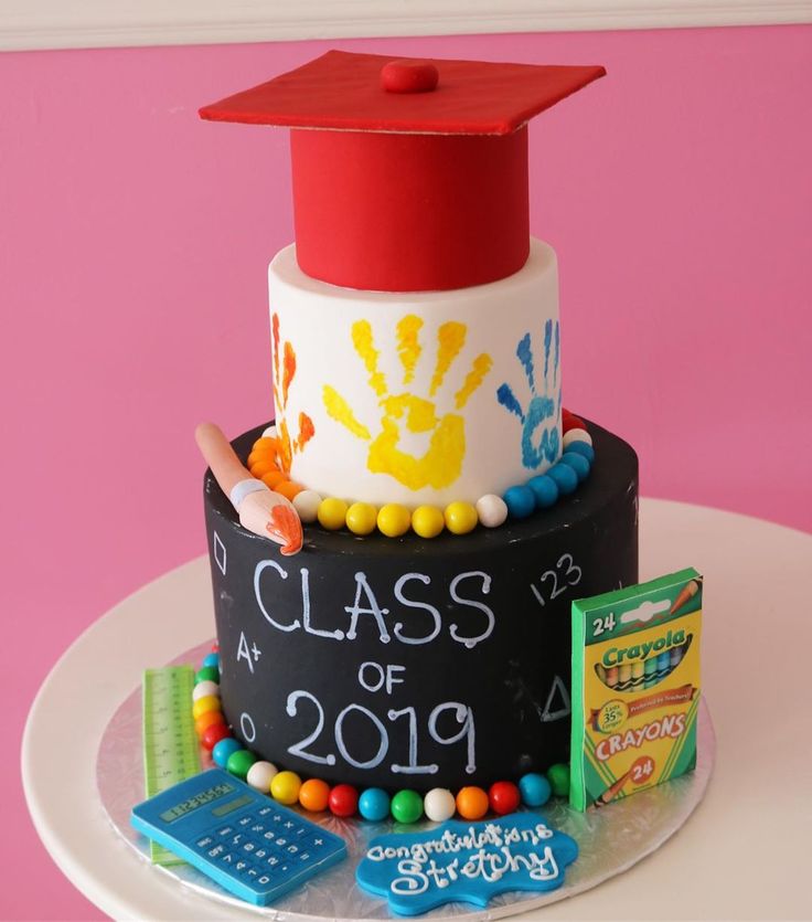 a graduation cake with handprints on it and a red cap atop the top