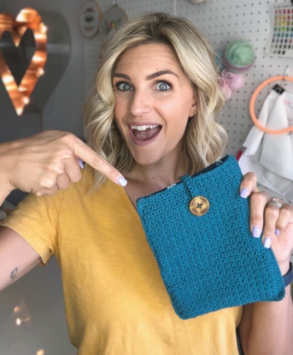 a woman holding up a blue purse in front of her face and pointing at it