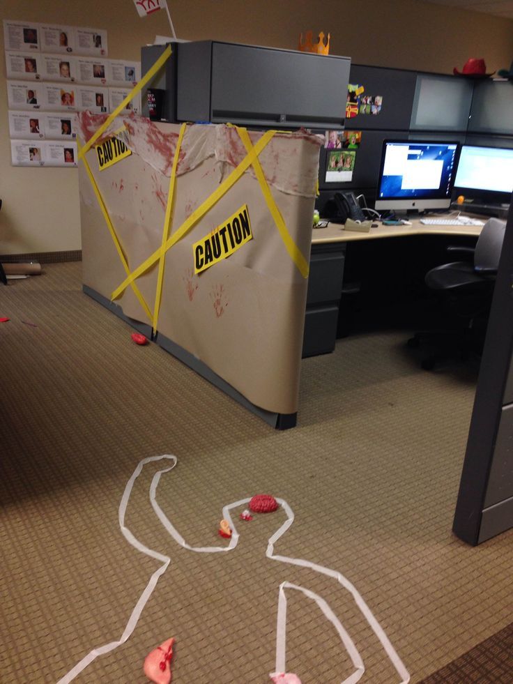 an office cubicle decorated with paper cut out of the body and words caution on the floor