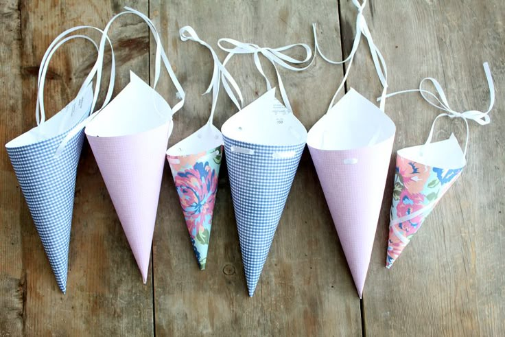 four cones are lined up on a wooden floor and tied to strings with white string