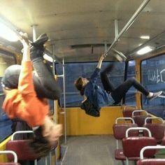 two people hanging upside down on a bus