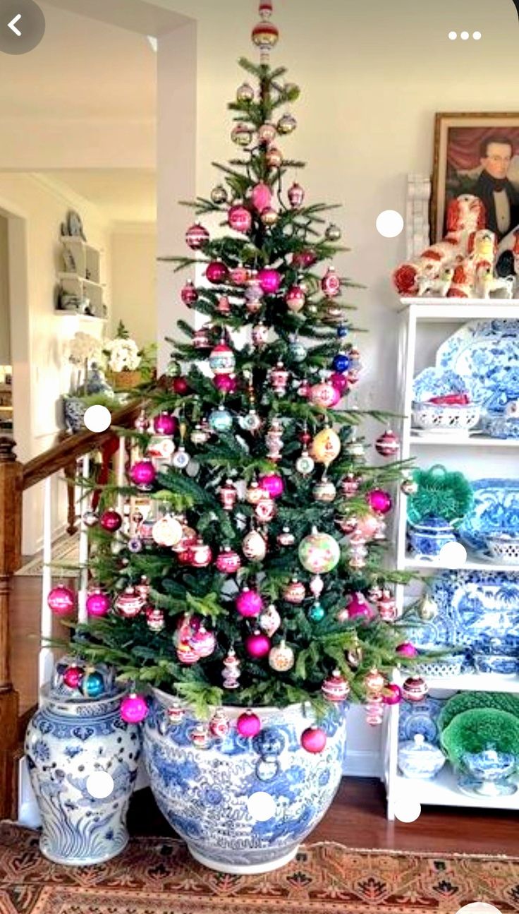 a decorated christmas tree in a blue and white vase next to other decorative items on display