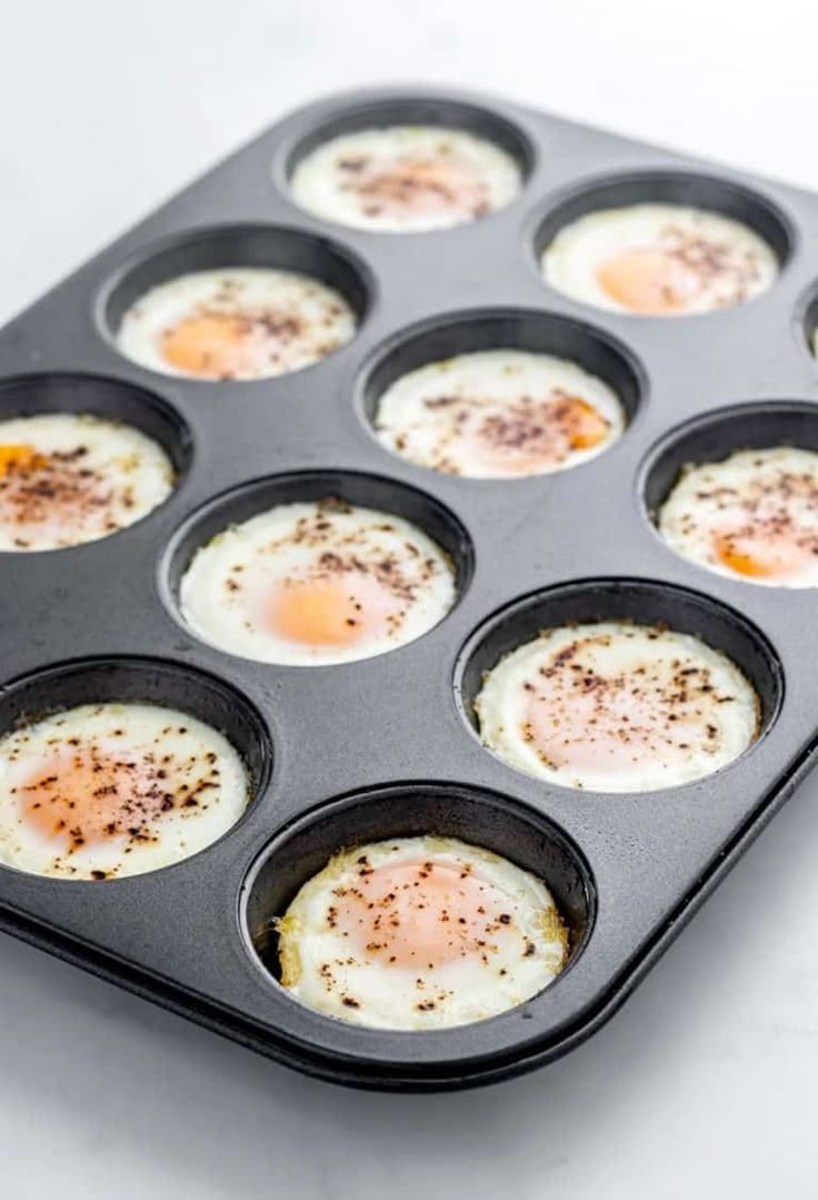 eggs in a muffin pan with seasoning on top, ready to be cooked