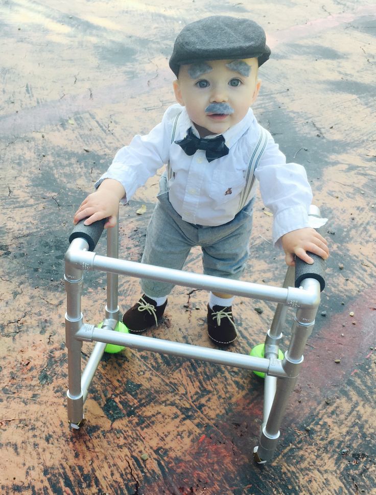 a little boy in a hat and bow tie standing on a metal step ladder with his hands on the handle bars