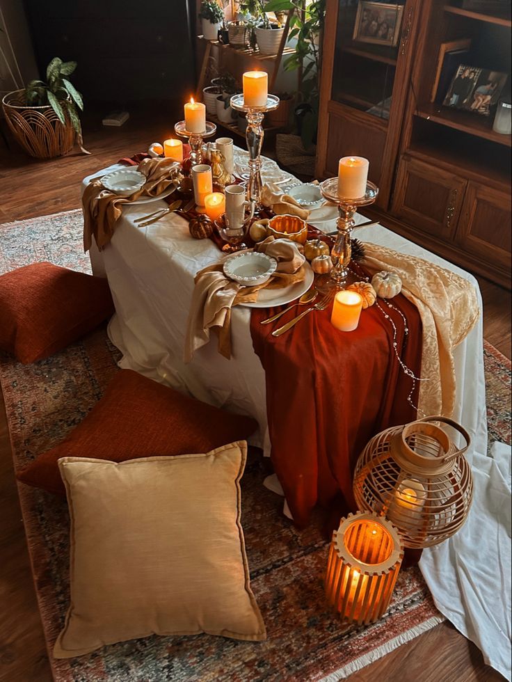 a table with candles and plates on it in the middle of a living room area