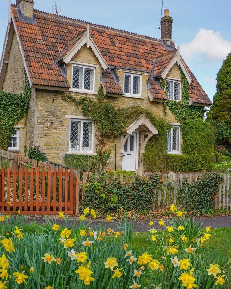 a house with flowers in front of it and a wooden fence around the yard area