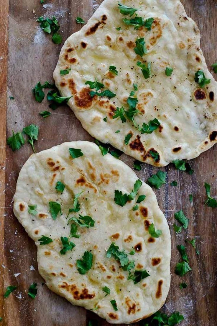 two flat breads on a cutting board with parsley