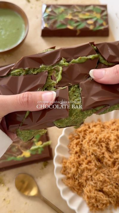 a person holding a chocolate bar over some food