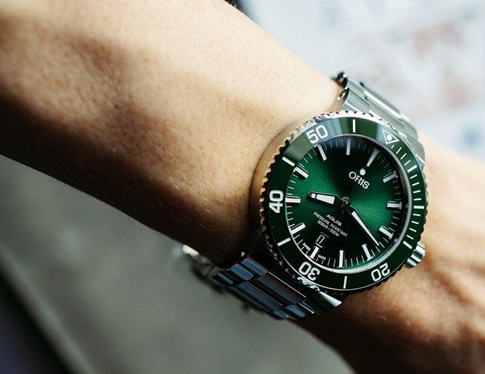 This Oris Aquis Date men's watch draws inspiration from the most versatile models in the history of the brand. The watch has a distinctive green dial inside a 43.5mm case crafted of stainless steel with a green, rotating 12-hour bezel. The self-winding mechanical movement, SW 200-1, features a sapphire crystal, date and second hand. The watch is water-resistant to 300 meters, and the stainless steel bracelet secures with a folding clasp and safety catch. Classic Green Chronometer Watch, Timeless Green Chronograph Watch, Classic Green Watch Accessories With Chronometer, Timeless Green Watch Accessories With Metal Dial, Green Analog Display Watch Accessories With Round Dial, Green Chronograph Watches For Formal Occasions, Green Chronometer Watch With Timeless Style, Timeless Green Chronometer Watch, Green Chronometer Watch With Round Dial