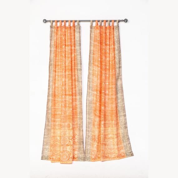 an orange and white curtain hanging on a metal rod in front of a white wall