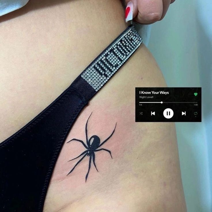 a woman's stomach with a black spider tattoo on it and an mp3 player next to her