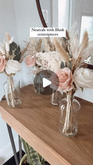 three vases filled with flowers sitting on top of a wooden table next to a mirror