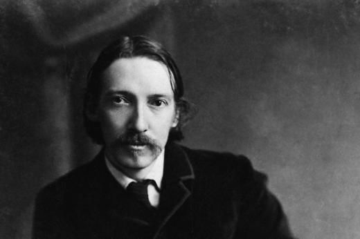 black and white photograph of a man with long hair wearing a suit, tie and jacket