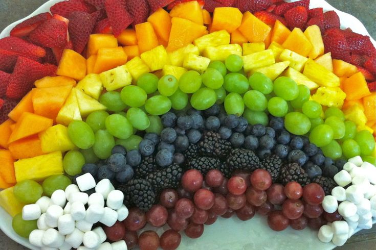 a plate filled with fruit and marshmallows in the shape of a rainbow