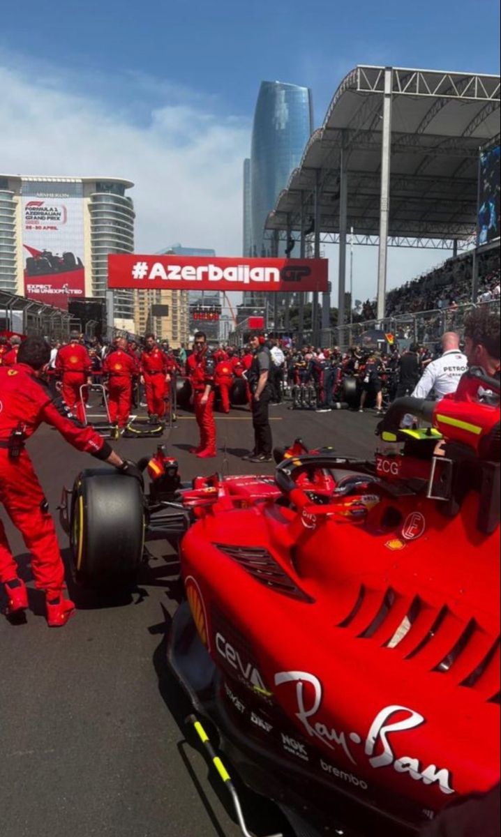 a red race car is being worked on by mechanics in front of the pit area