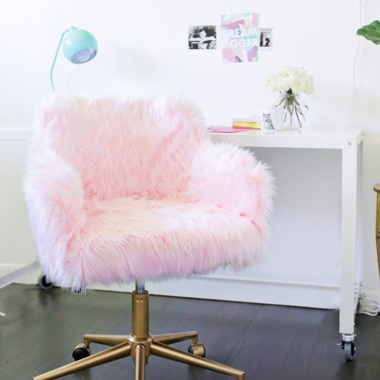 a pink chair sitting on top of a wooden floor next to a white desk with a potted plant