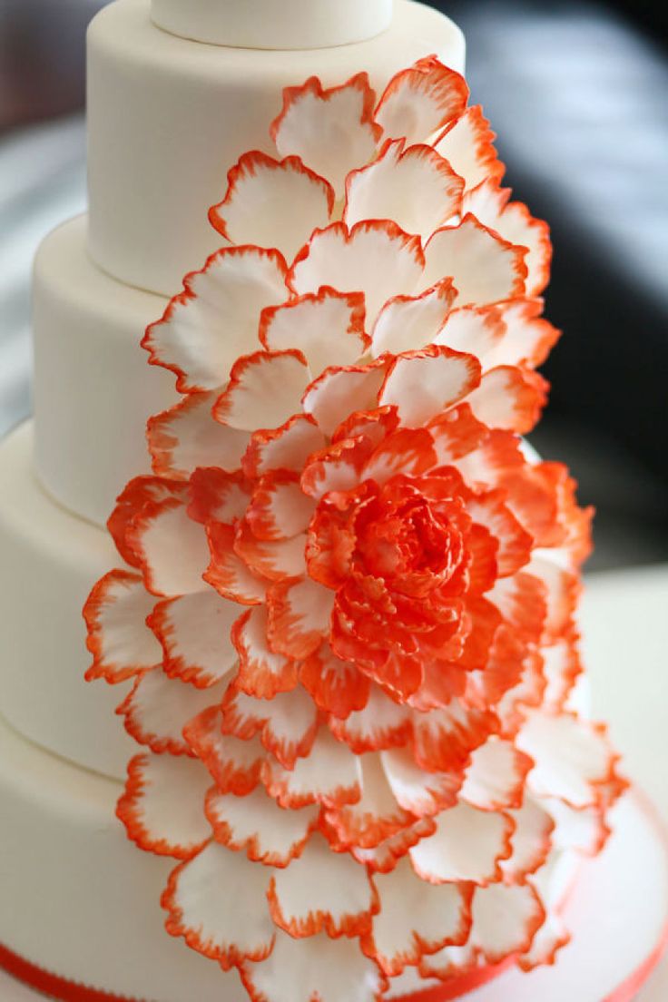 an orange and white wedding cake decorated with flowers