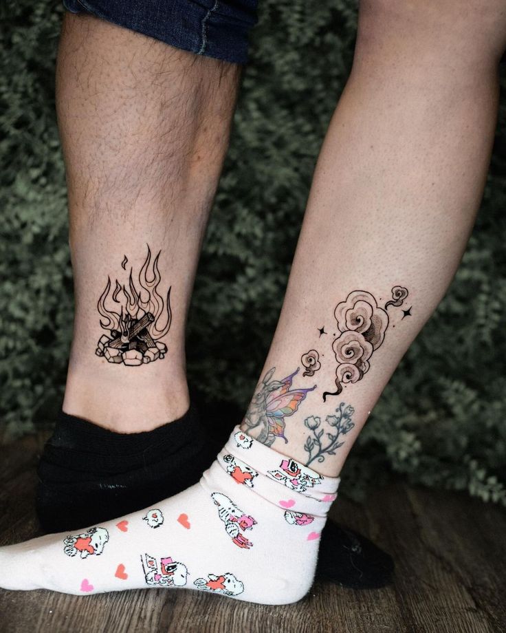 two people with tattoos on their legs standing next to each other, both wearing socks