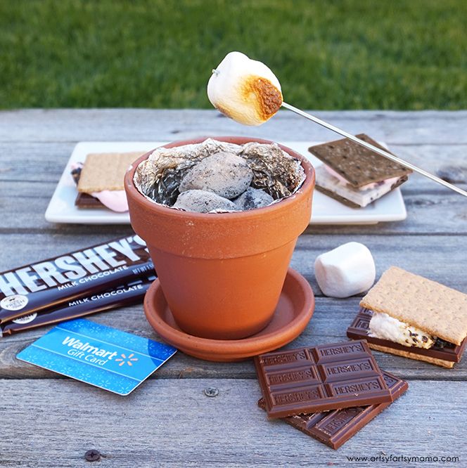 a potted plant sitting on top of a wooden table next to chocolate bars and marshmallows