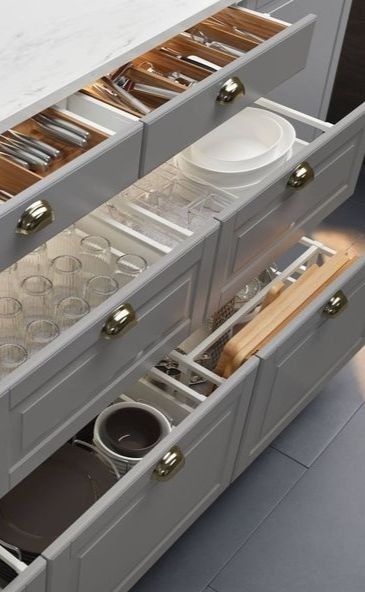 an open drawer with dishes and utensils in it on the side of a kitchen counter