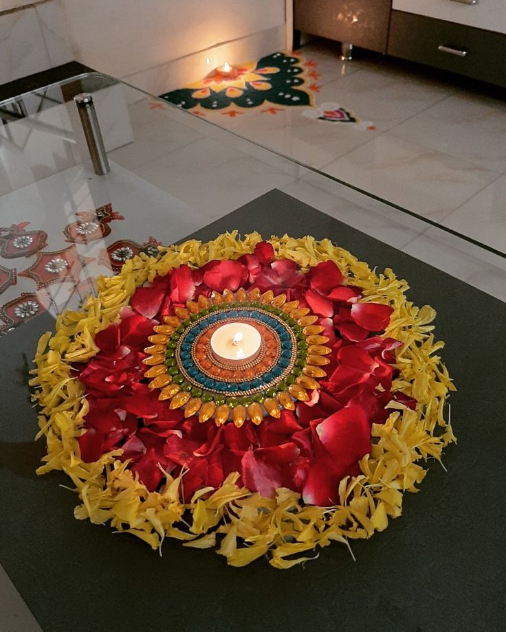 a candle is lit in the center of a circular arrangement of flowers and leaves on a table