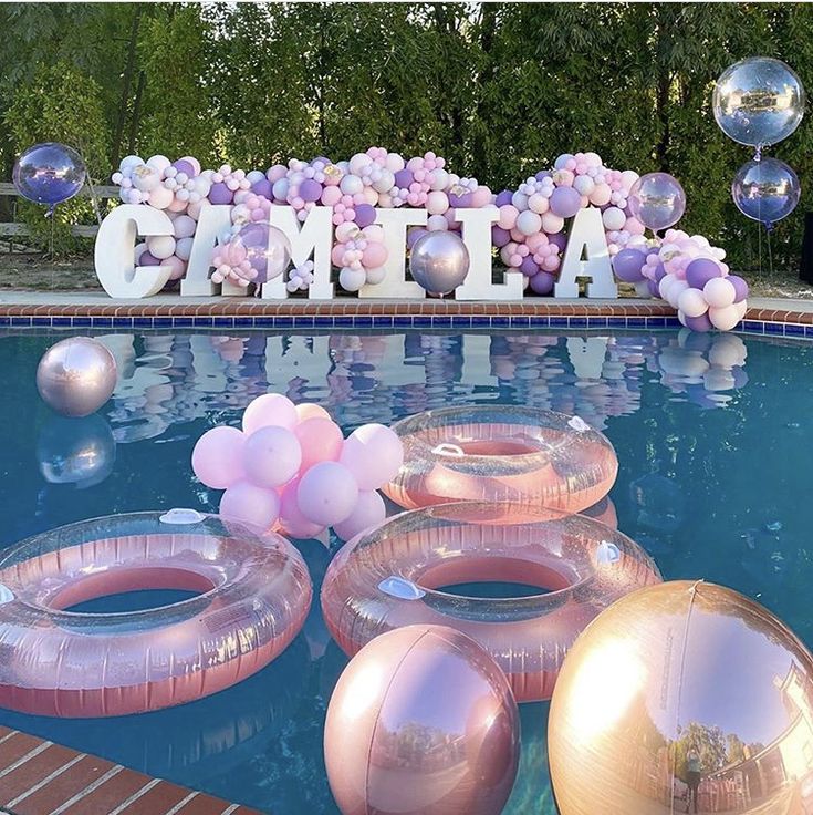 balloons floating on top of a swimming pool next to an inflatable balloon sign