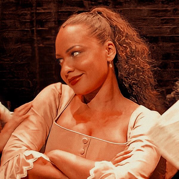 a woman with her arms crossed sitting on a couch in front of a brick wall