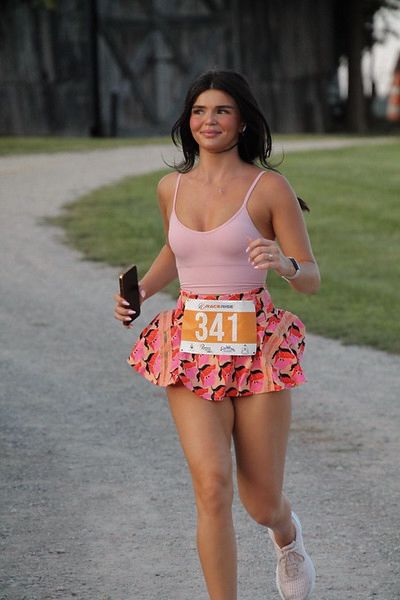 a woman running down a path in a pink top and skirt with the number 34 on it