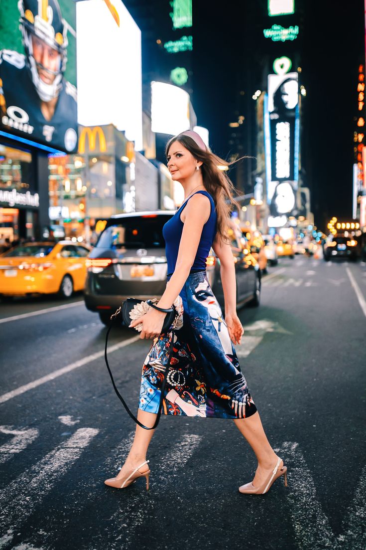 a woman crossing the street in new york city at night with her hair blowing back