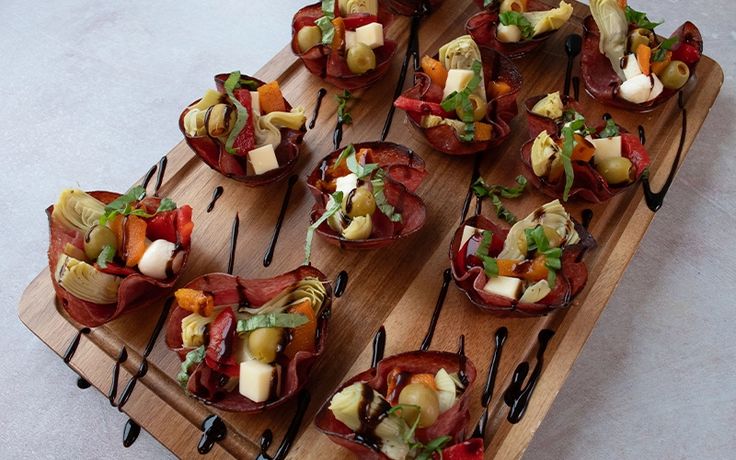 a wooden tray topped with lots of different types of appetizers on top of each other