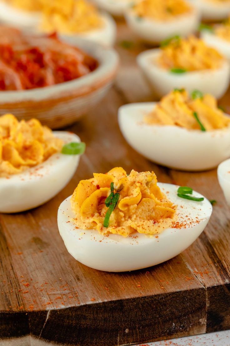 several deviled eggs are sitting on a wooden board