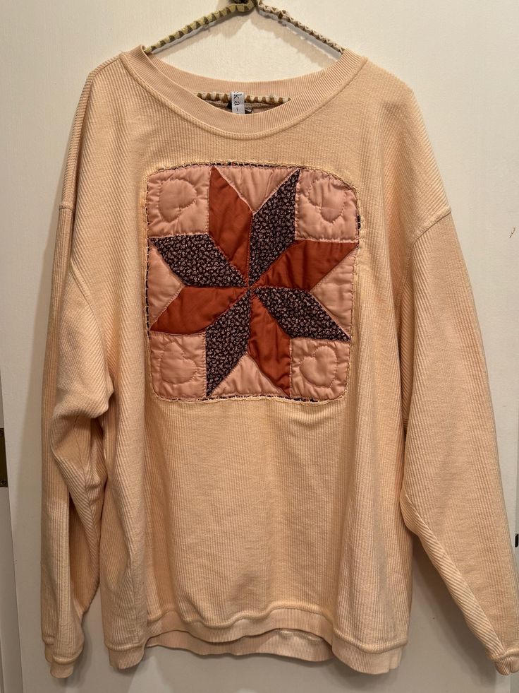 a sweater hanging on a hanger in front of a door with an embroidered star