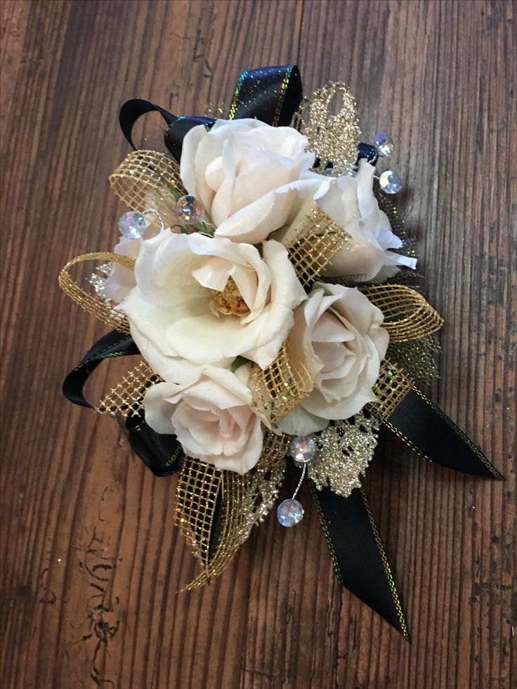 a bridal corsage with white flowers and black ribbon on a wooden table