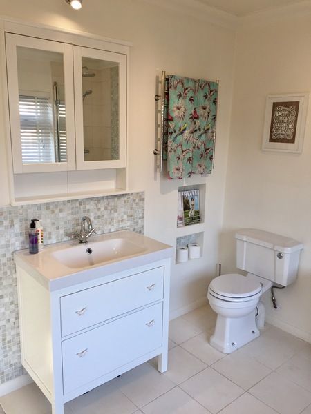 a white bathroom with a toilet, sink and mirror in it's center area