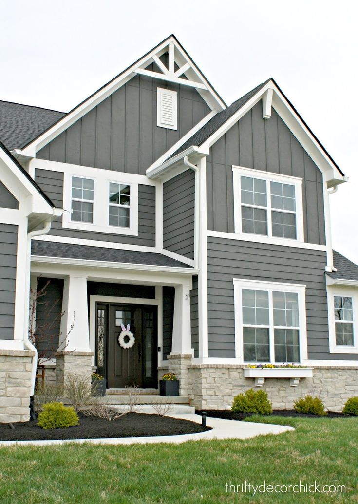 a gray house with white trim on the front door and two story windows is shown