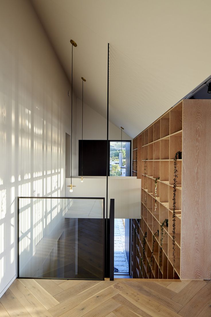 an empty room with wooden floors and shelves on the wall, next to a large window