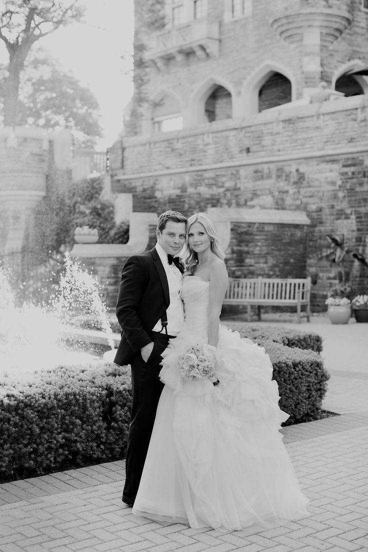 a bride and groom pose in front of a fountain