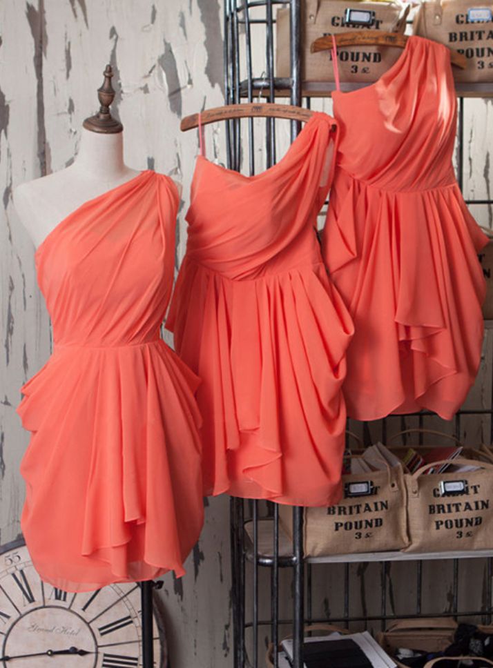 two bridesmaid dresses hanging on a rack in front of a wall with other mannequins