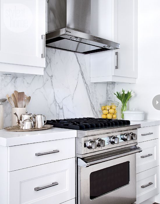 a stove top oven sitting inside of a kitchen next to white cupboards and drawers